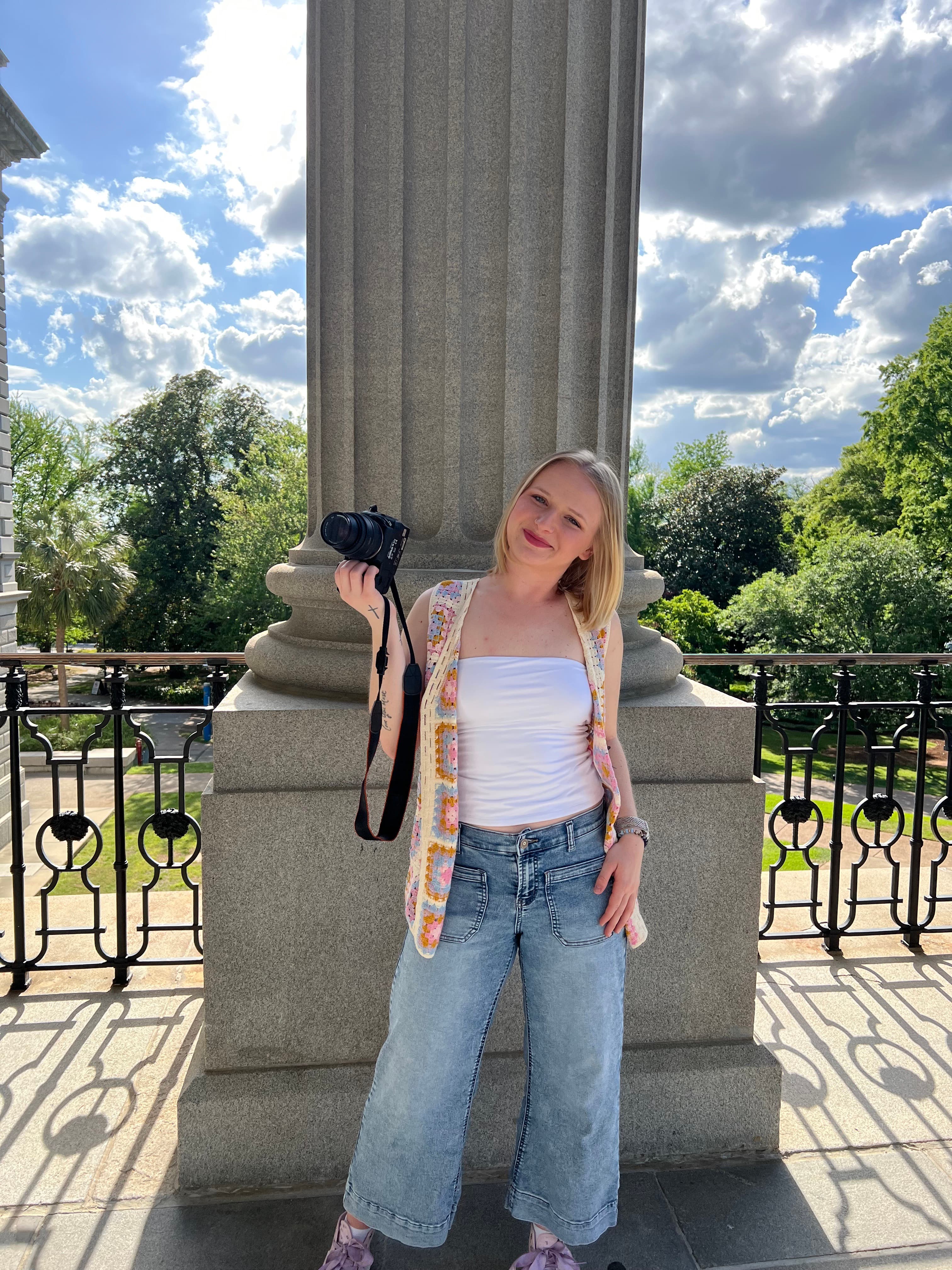 Sydney Graham smiling outdoors while holding her camera