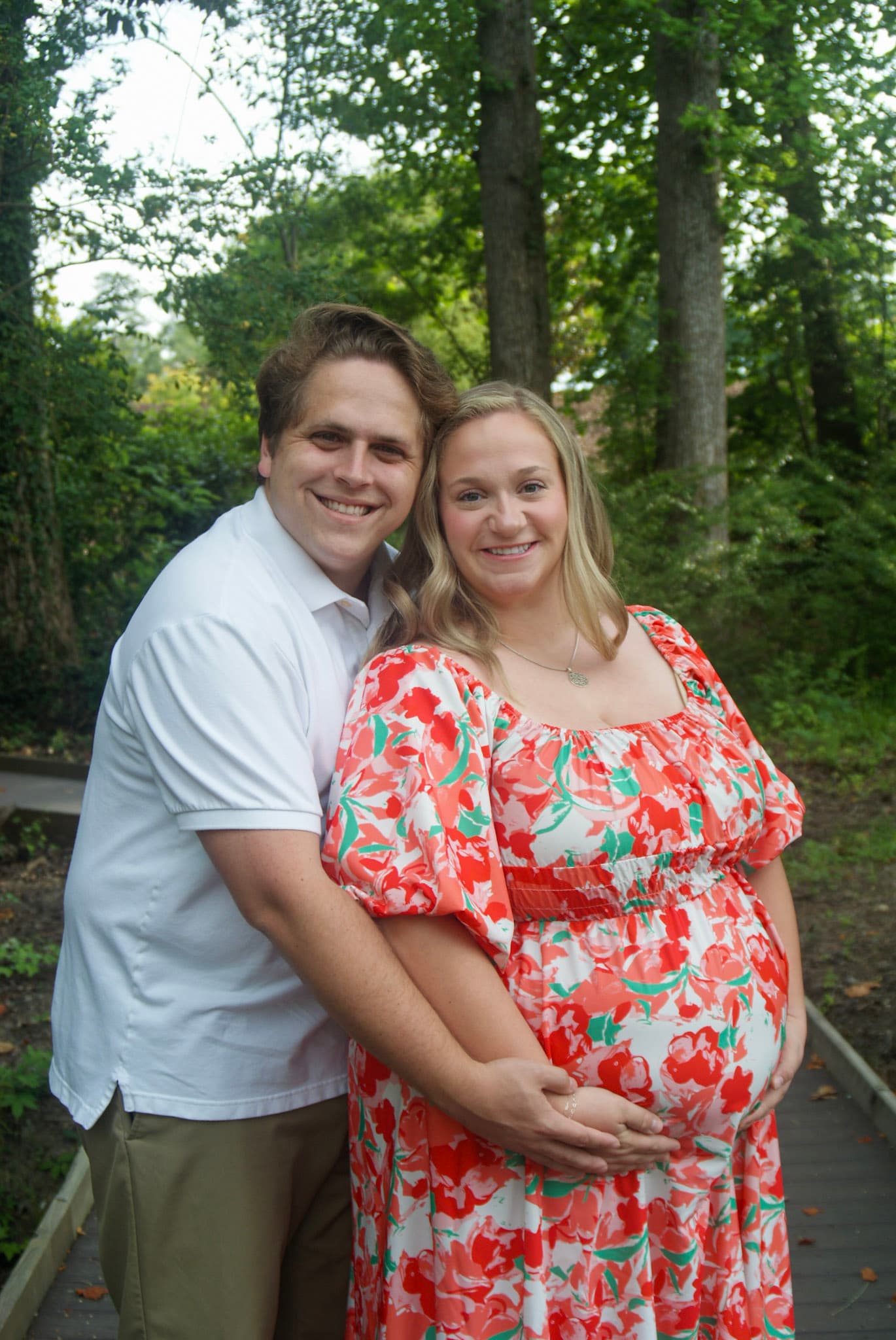 Smiling couple maternity portrait on a wooded path