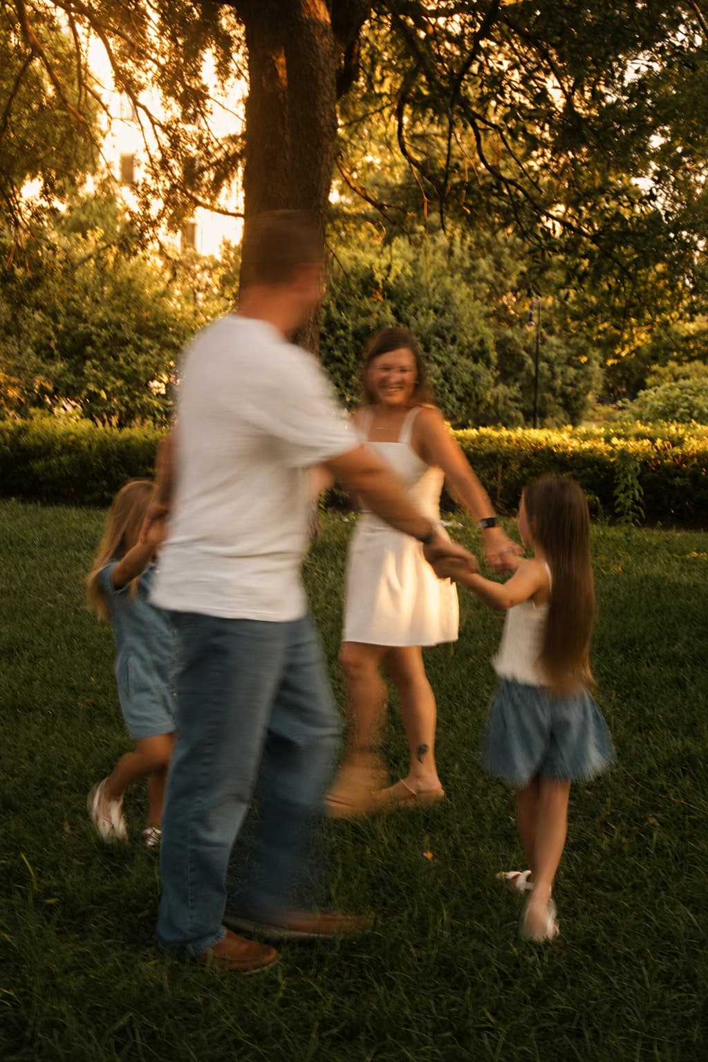 Family holding hands and spinning together at golden hour