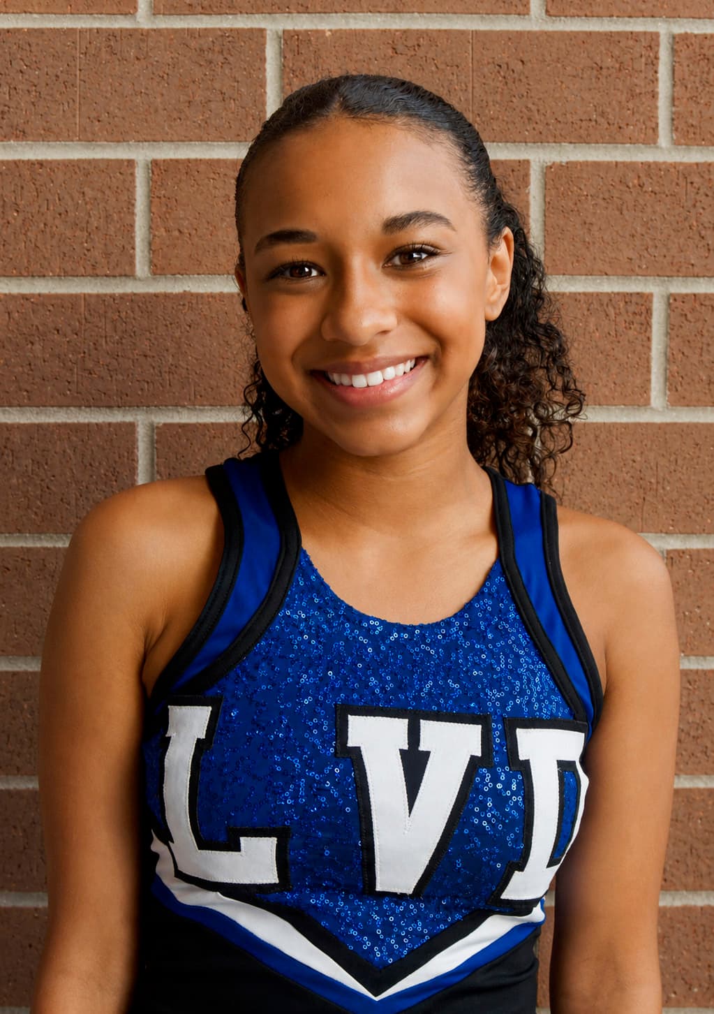 Smiling headshot portrait against a brick wall