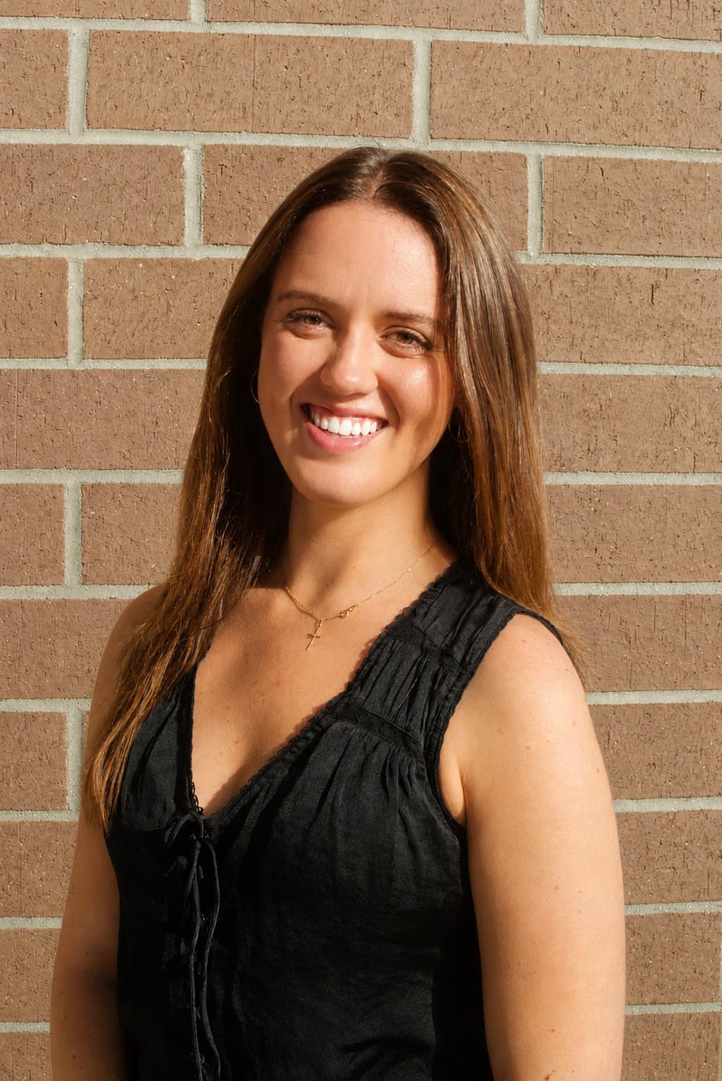 Professional headshot portrait with warm brick backdrop
